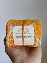 Load image into Gallery viewer, Rolled up tea towel held in palm of hand showing that these flour sack tea towels are lint free, 100% cotton, made in USA.
