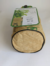 Load image into Gallery viewer, This recycled seed sack was constructed into this little bag shown here with a round shaped bottom and black piping as trim. The Round bag holds the soil and seeds that come in the kit for growing basil.