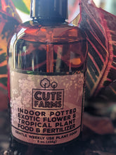Load image into Gallery viewer, Plant food bottle for exotic flower and tropical plants shown with a croton plant in background.