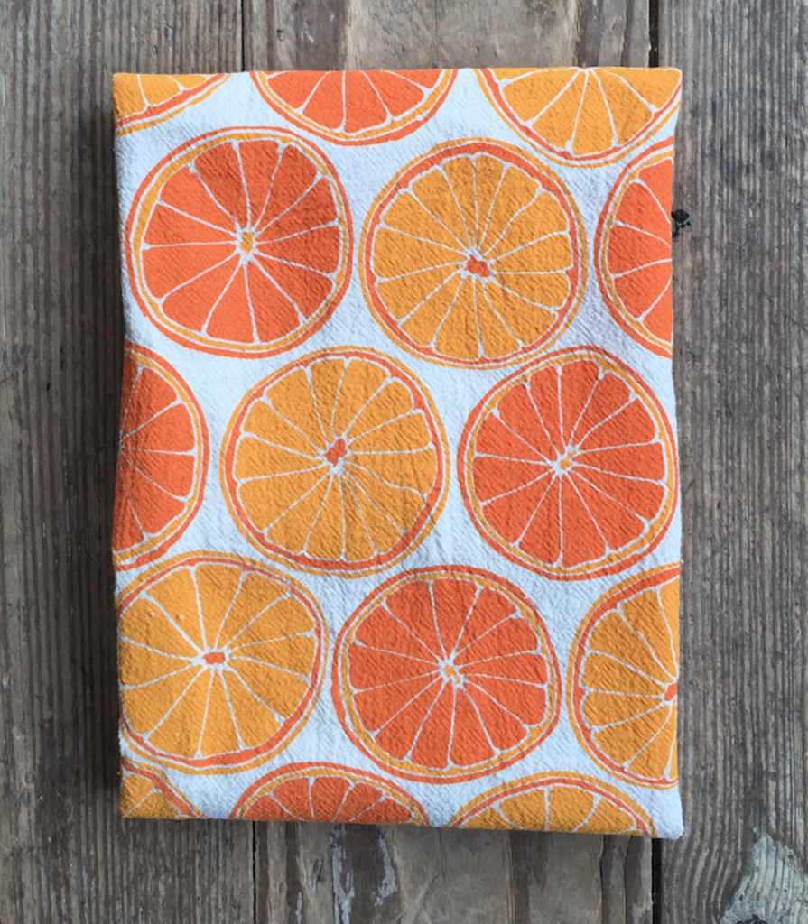 Light and dark orange colors make up the pattern of sliced oranges on an unbleached cotton tea towel 